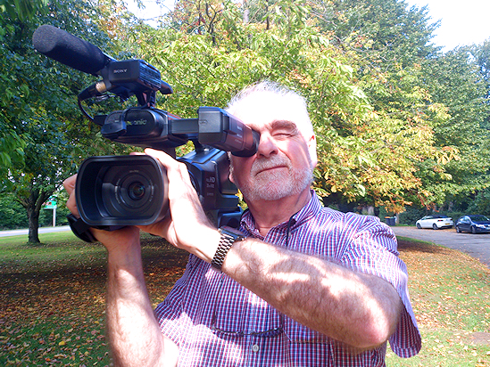 A cameraman films under some trees